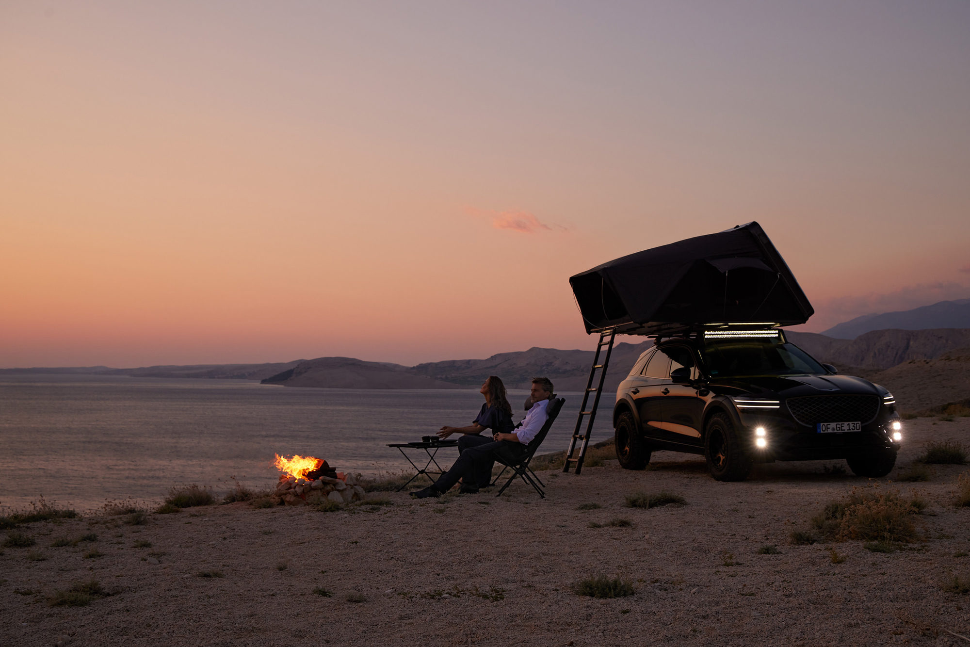 Genesis vehicle with rooftop tent IKamper at a remote campsite during sunset