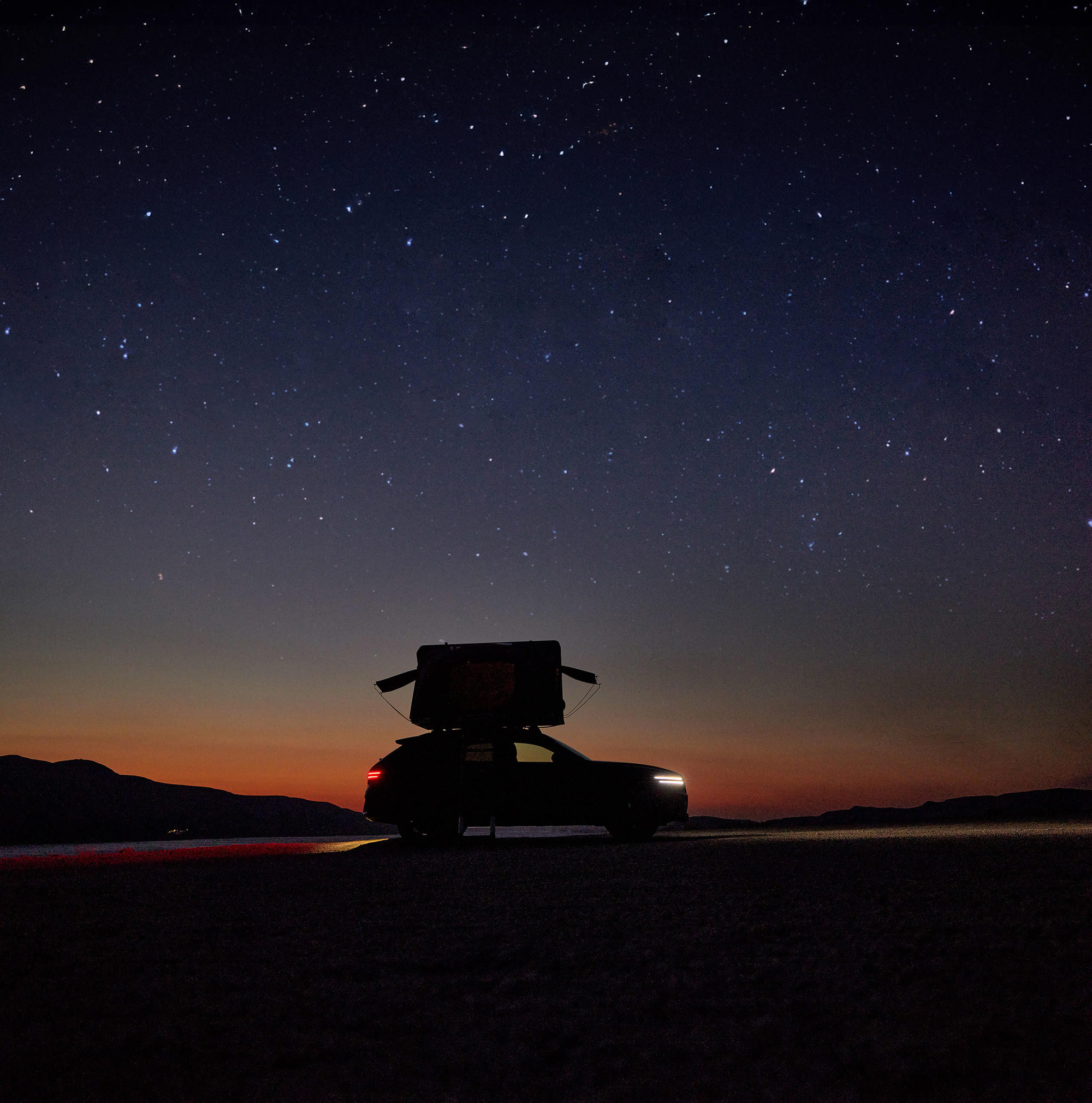 Genesis vehicle with rooftop tent IKamper under a starry night sky