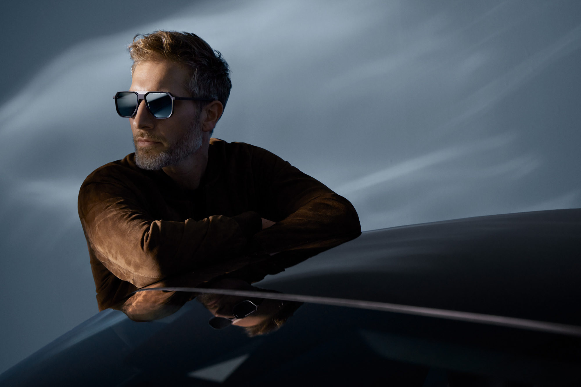 model wearing Porsche Design glases leaning on asports car in a studio 