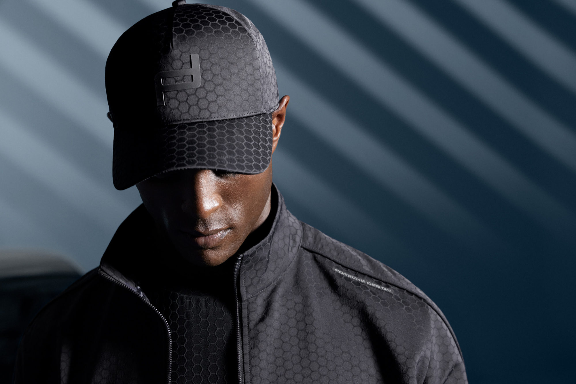 Close-up portrait of a male coloured model wearing black Porsche Design sportswear and cap